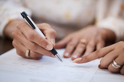 Hands hovering over paperwork being filled in